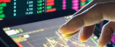 fingers on tablet with stock ticker in background